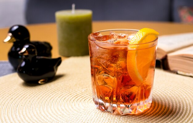 Un vaso de whisky sobre la mesa con rodajas de limón y hielo vista lateral