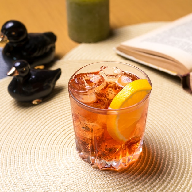 Un vaso de whisky sobre la mesa con rodajas de limón y hielo vista lateral