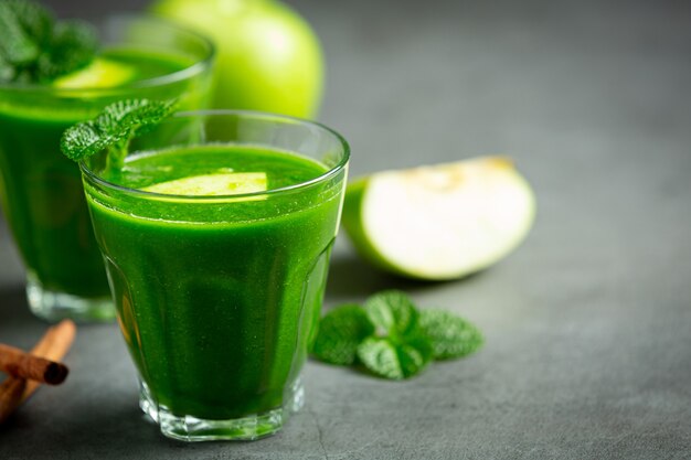 Vasos de batido saludable de manzana verde junto a manzanas verdes frescas