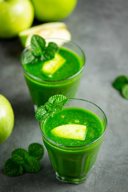 Vasos de batido saludable de manzana verde junto a manzanas verdes frescas