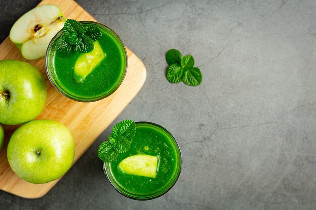 Vasos de batido saludable de manzana verde junto a manzanas verdes frescas