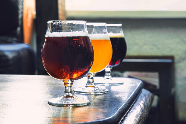 Vasos de diferentes tipos de cerveza oscura y clara en la mesa de madera en línea.