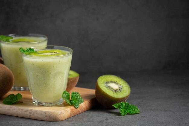 Vasos de jugo de kiwi en tabla de cortar de madera