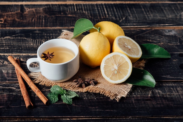 Vasos de té con limón, limones en rodajas sobre una tabla de cortar