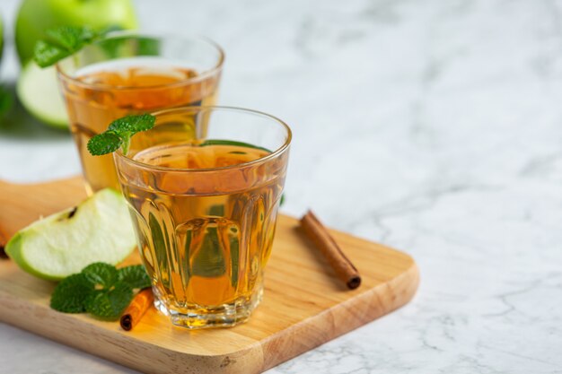 Vasos de té saludable de manzana verde junto a manzanas verdes frescas