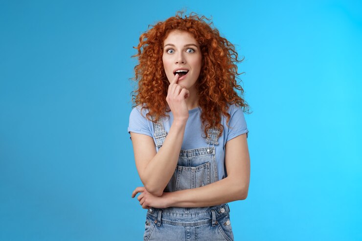 Foto gratuito vaya, dime más. chica excitante escuchar detalles de pie asombrado deseo probar nuevo sabor de helado toque labio adicto mirar fijamente cámara aspiración quiero esa cosa de pie curiosa emocionado fondo azul.