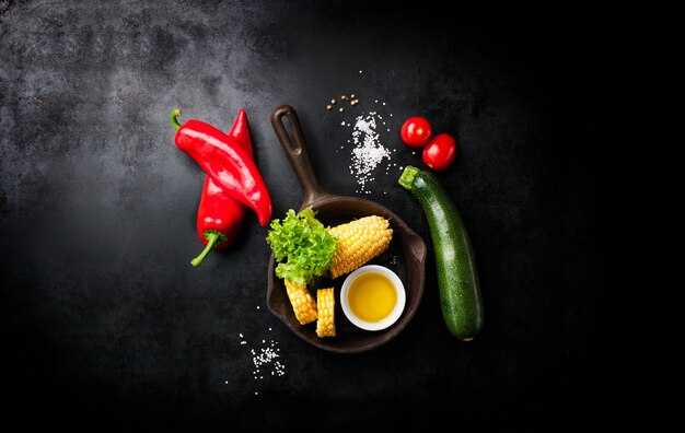 Vegetales y un cuchillo italiano puestos en una mesa negra