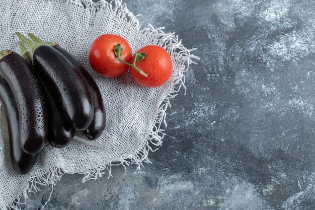 Vegetales orgánicos. Berenjenas moradas con tomate sobre fondo gris.