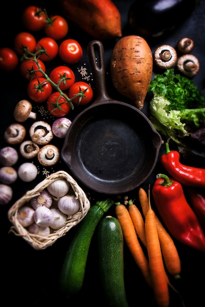 Foto gratuita vegetales varios rodeando una sartén negra vacia