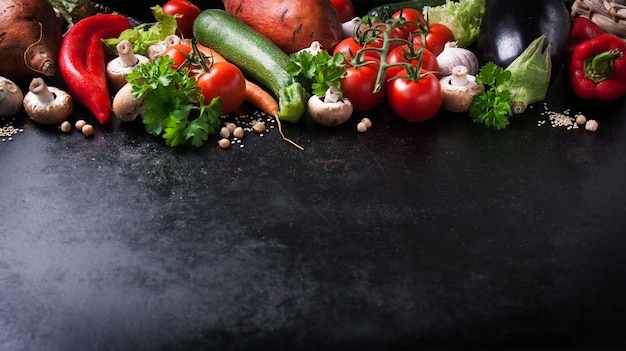 Vegetales varios sobre una mesa negra con espacio para un mensaje