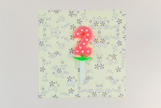 Vela de dos años en papel floral del arte sobre el contexto coloreado