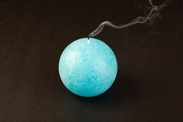 Una vela de forma redonda con vista frontal estalló de color azul, diseñada en el fondo oscuro, brillante decoración de fuego