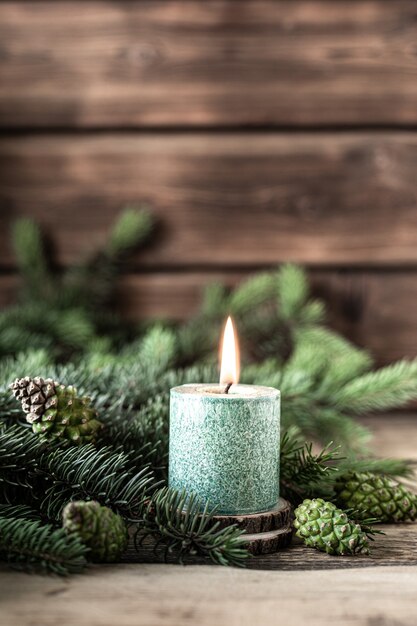 Vela de Navidad verde con ramas de abeto y conos en mesa de madera