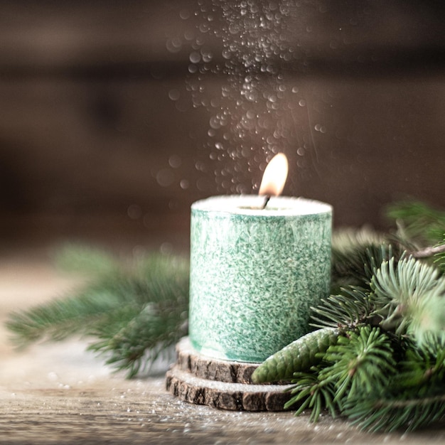 Vela de Navidad verde con ramas de abeto y conos en mesa de madera