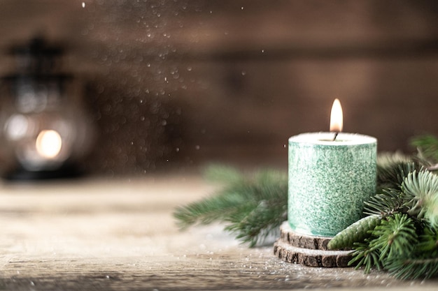 Vela de Navidad verde con ramas de abeto y conos en mesa de madera