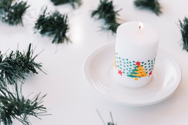 Vela en plato con ramas de arbol de navidad