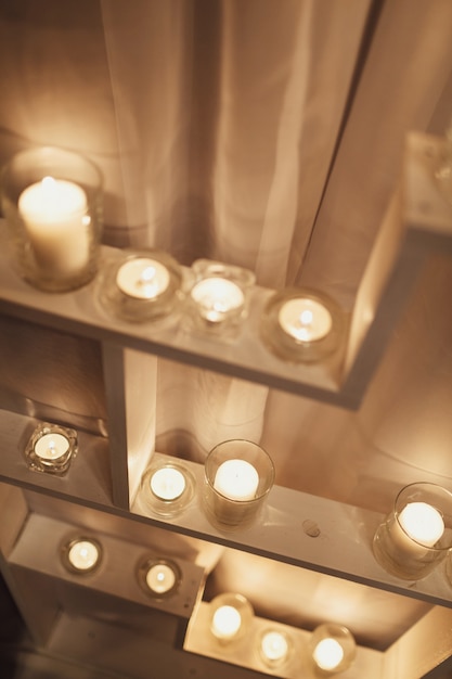 Las velas blancas brillan en los estantes
