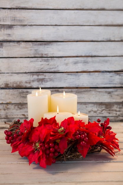 Foto gratuita velas blancas encendidas con flores rojas