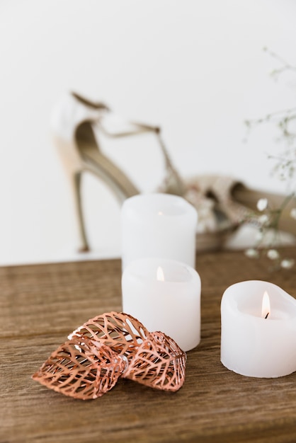 Velas blancas iluminadas en mesa de madera.