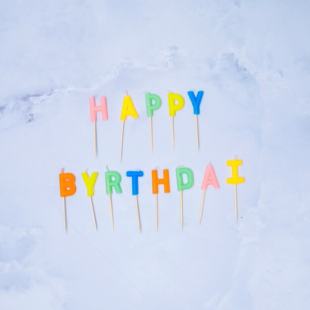 Velas coloridas del feliz cumpleaños en el fondo de mármol