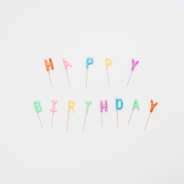 Velas coloridas de las letras del feliz cumpleaños en el fondo blanco