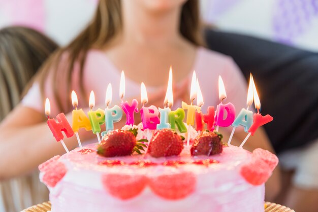 Velas de cumpleaños brillantes multicolores en tarta de fresas