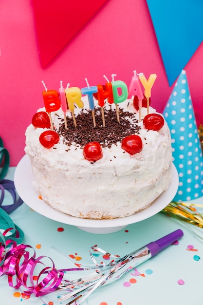 Velas de cumpleaños en pastel blanco con decoración de fiesta