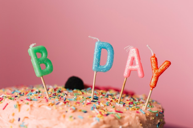 Foto gratuita velas de cumpleaños en la torta contra el fondo de color