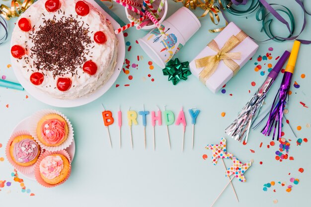 Velas de cumpleaños de Word con accesorios de fiesta y pastel sobre fondo azul