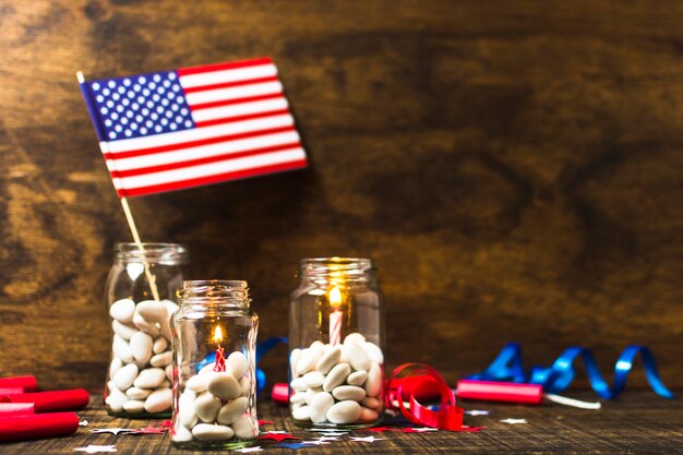 Velas encendidas y bandera de Estados Unidos en el tarro de caramelos en el escritorio de madera