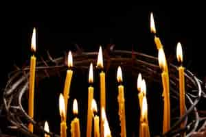 Foto gratuita velas encendidas y corona de espinas con fondo oscuro