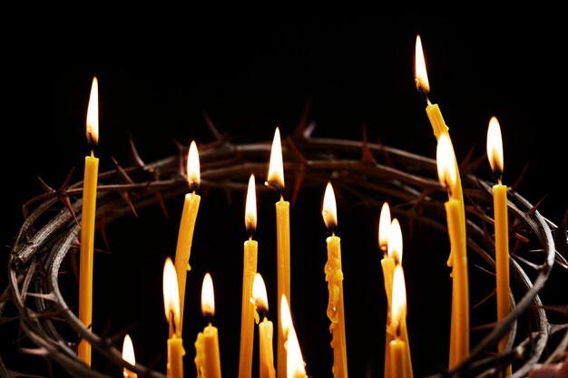 Velas encendidas y corona de espinas con fondo oscuro