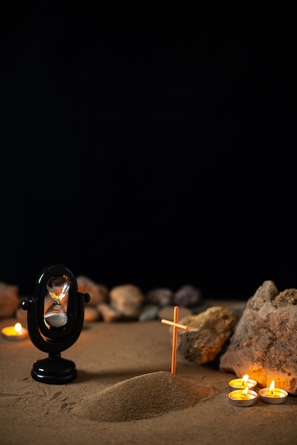 Foto gratuita velas encendidas con piedras y pequeña tumba en la arena como recuerdo de la muerte del funeral