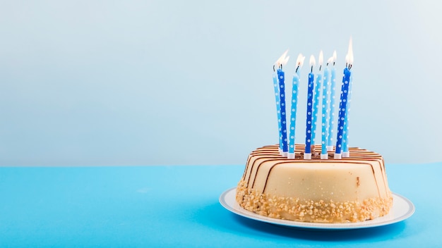 Velas encendidas sobre el delicioso pastel sobre fondo azul