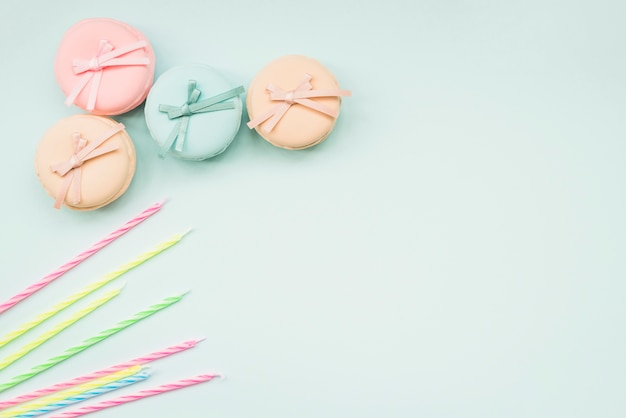 Velas y macarons rayados con el arco en el fondo blanco