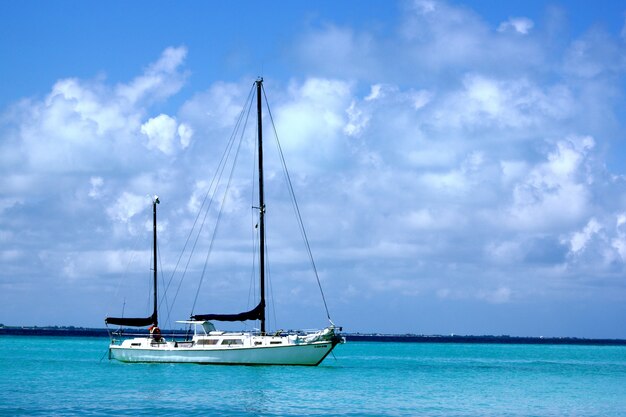 Velero en el mar bajo la luz del sol y un cielo nublado durante el día