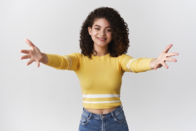 Foto gratuita ven a darme un abrazo besos atractiva, amable, agradable, joven, de pelo rizado, mestiza, estirar las manos hacia la cámara, quiero abrazar, alcanzar, persona, sonriente, invitar, abrazos, fondo blanco