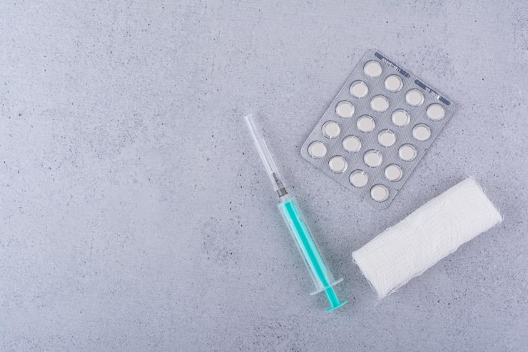 Foto gratuito vendaje, jeringa y píldoras médicas sobre fondo de mármol. foto de alta calidad