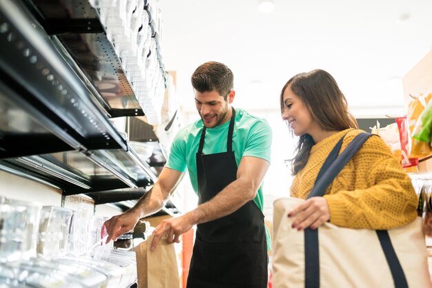 Vendedor confiado empacando comida para mujer en la tienda de comestibles