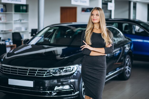 Vendedor femenino en una sala de exposición de automóviles junto al automóvil