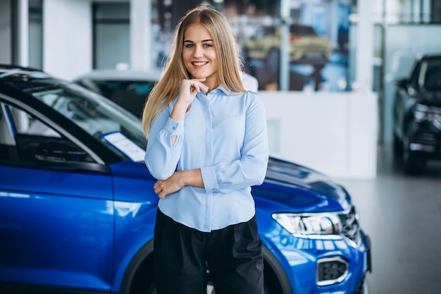 Vendedor femenino en una sala de exposición de automóviles junto al automóvil