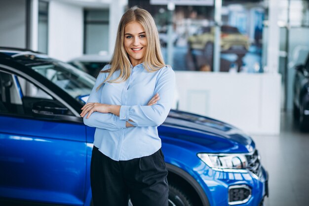 Vendedor femenino en una sala de exposición de automóviles junto al automóvil