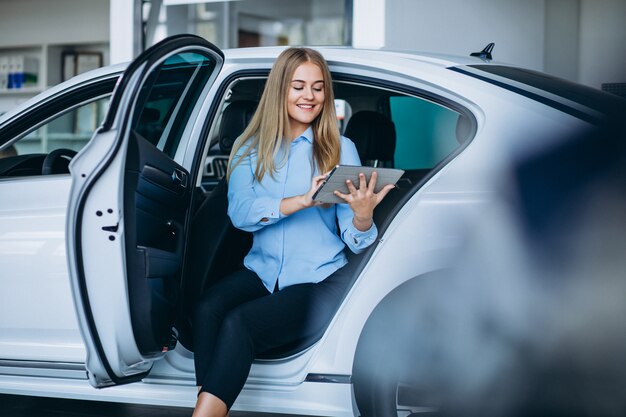 Vendedor femenino en una sala de exposición de automóviles junto al automóvil