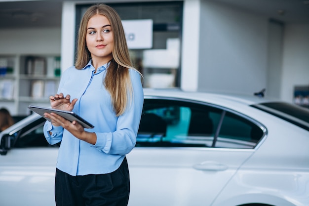 Vendedor femenino en una sala de exposición de automóviles junto al automóvil