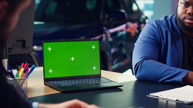 Vendedor que utiliza una computadora portátil de pantalla aislada para presentar opciones de complementos para automóviles