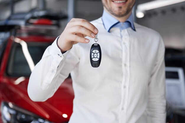 Vendedor sosteniendo la llave del coche en el showroom