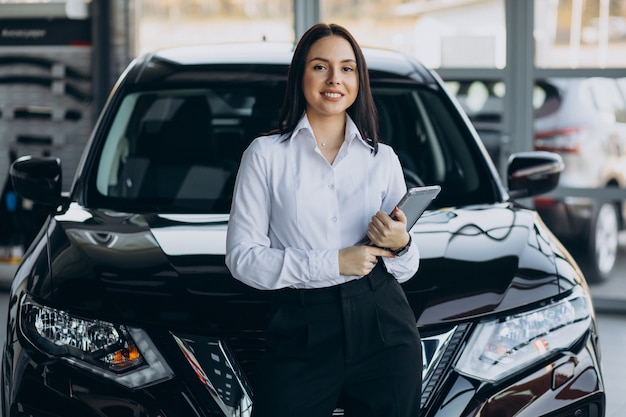 Foto gratuita vendedora en sala de exposición de coches vendiendo coches