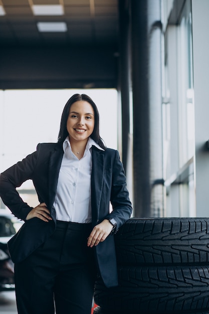 Foto gratuita vendedora en sala de exposición de coches vendiendo coches