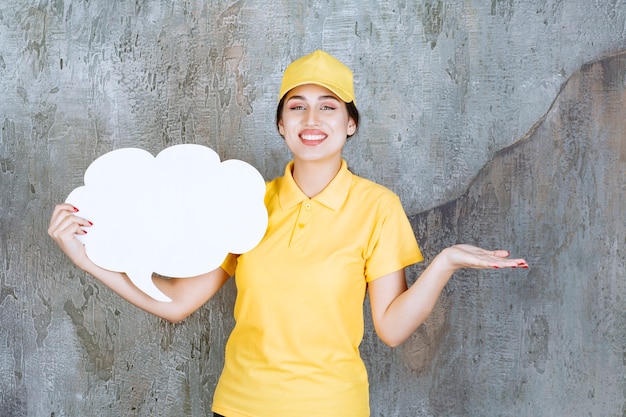 Una vendedora en uniforme amarillo sosteniendo un tablero de información de forma de nube.