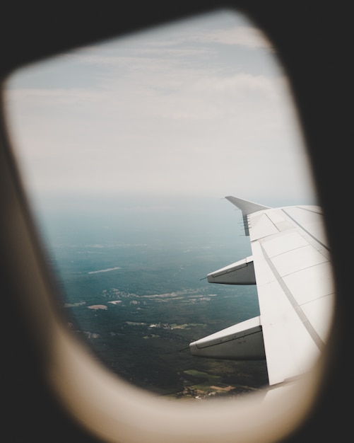 La ventana del avión con la vista de los campos verdes de arriba y el ala derecha